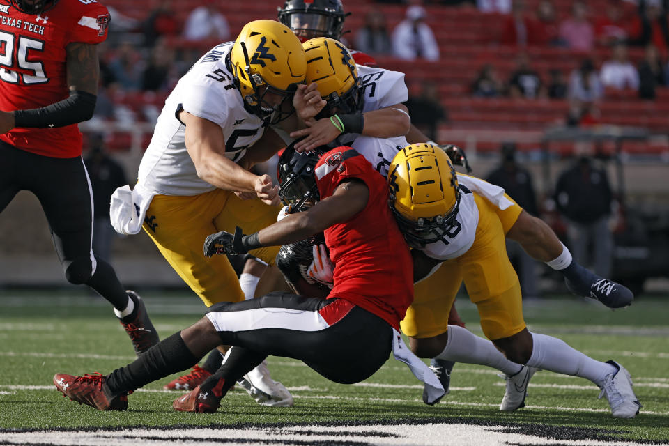 West Virginia's Jake Abbott (51) and West Virginia's Winston Wright Jr. (16) tackle Texas Tech's Adrian Frye (7) during the first half of an NCAA football game on Saturday, Oct. 24, 2020, in Lubbock, Texas. (AP Photo/Brad Tollefson)