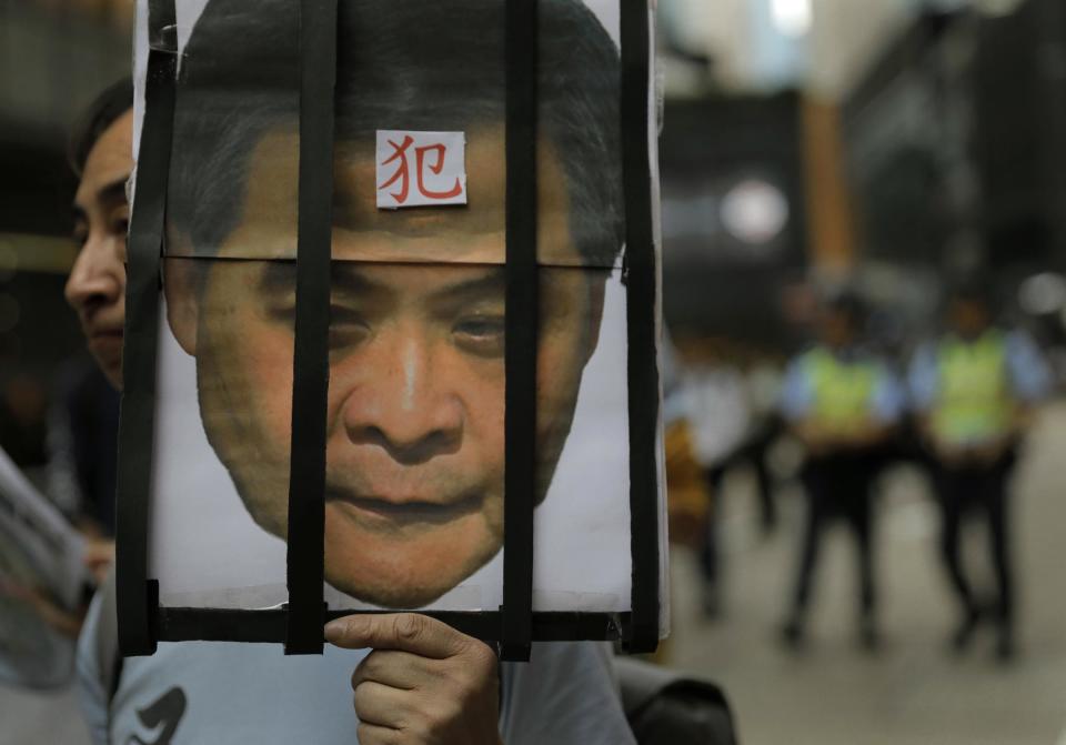 A protester raises a picture of Chief Executive Leung Chun-ying with a Chinese word "Prisoner" on his face during a rally on the first day of 2017 in Hong Kong, Sunday, Jan. 1, 2017. They protest against Beijing's interpretation of Basic Law and Hong Kong government's bid to ban pro-democracy lawmakers from taking office. They also demand true universal suffrage, which is not happening in the coming chief executive election in March. (AP Photo/Vincent Yu)