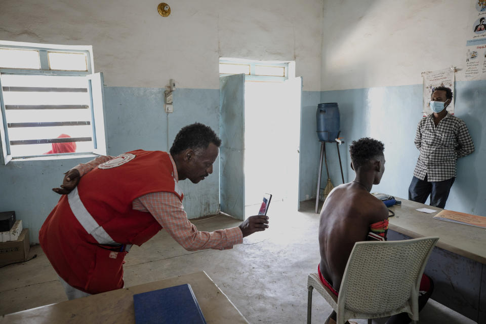 Surgeon and doctor-turned-refugee, Dr. Tewodros Tefera, uses his mobile phone camera to document the welts on the back from a beating by Eritrean soldiers of Adhanom Gebrehanis, a 20-year-old Tigrayan refugee from Korarit village, at the Sudanese Red Crescent clinic shortly after his arrival in Hamdayet, eastern Sudan, near the border with Ethiopia, on March 17, 2021. “It is definitely genocide,” he says. “If someone is being attacked for their identity, if they’re threatened to be vanished because of their identity, there is no other explanation for this.” (AP Photo/Nariman El-Mofty)