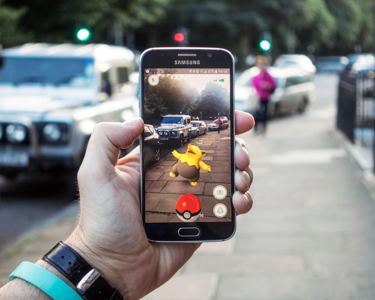 closeup of a man holding a Samsung S6 smartphone, playing Pokemon Go