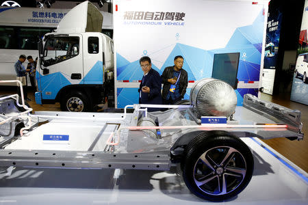 FILE PHOTO: Visitors looks at the frame of an electric vehicle next to a Foton autonomous truck at the stall of the BAIC Group automobile maker at the IEEV New Energy Vehicles Exhibition in Beijing, China October 18, 2018. REUTERS/Thomas Peter/File Photo