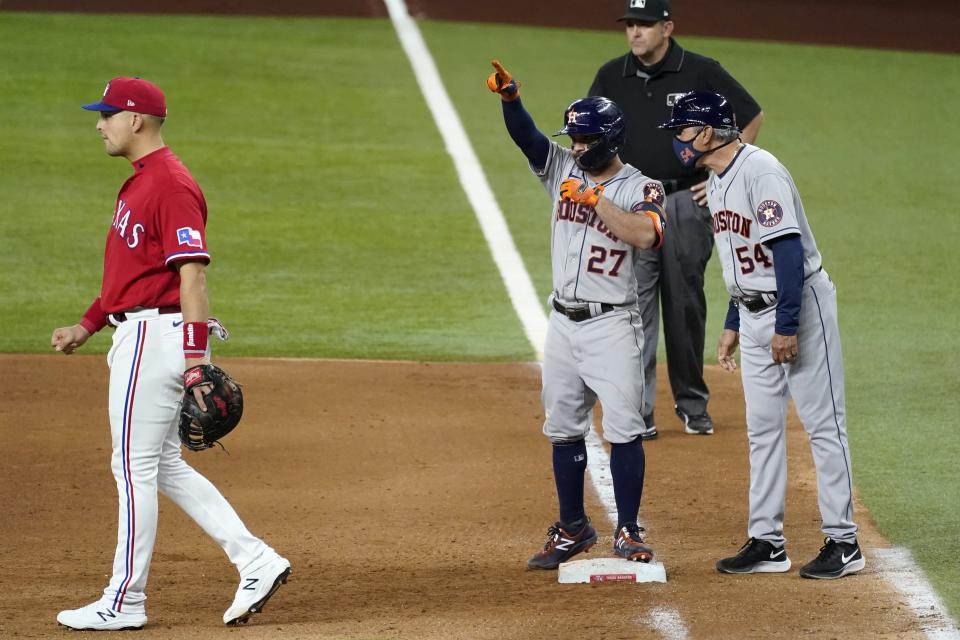 Texas Rangers first baseman Nate Lowe walks away as Houston Astros' Jose Altuve, center and coach Dan Firova (54) celebrate Altuve's RBI single during the eighth inning of a baseball game in Arlington, Texas, Friday, May 21, 2021. Umpire Brian Knight stands at rear. (AP Photo/Tony Gutierrez)