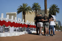 FILE - In this Oct. 1, 2019, file photo, people pray at a makeshift memorial for shooting victims in Las Vegas, on the anniversary of the mass shooting two years earlier. Two years after a shooter rained gunfire on country music fans from a high-rise Las Vegas hotel, MGM Resorts International reached a settlement that could pay up to $800 million to families of the 58 people who died and hundreds of others who were injured, attorneys announced Thursday, Oct. 3, 2019. (AP Photo/John Locher, File)