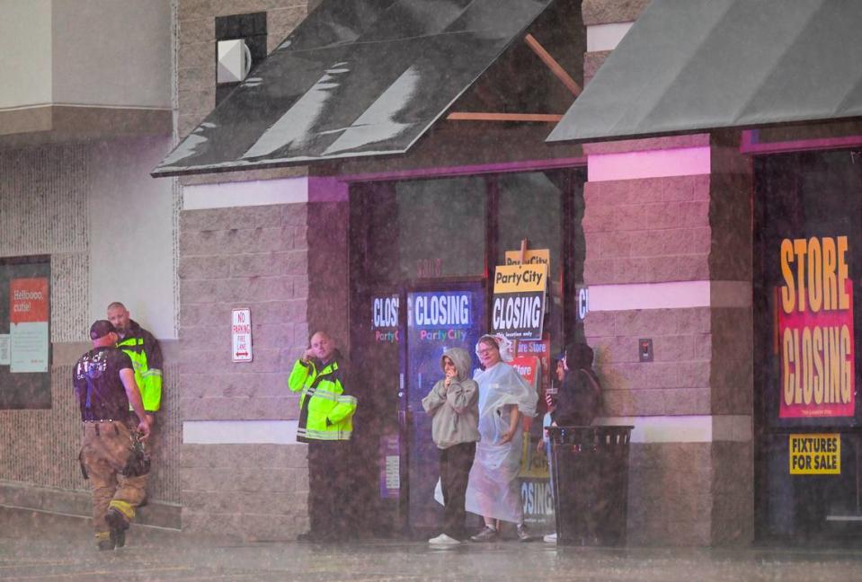 People huddled outside of a Party City store after power was knocked out when a severe storm moved through Merriam, Kansas, on Friday, July 14, 2023.