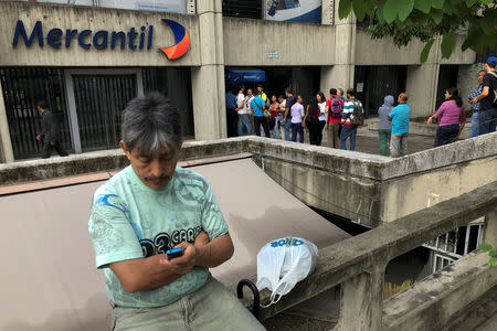 People queue to withdraw cash from automated teller machines (ATM) at a Mercantil bank branch in Caracas, Venezuela August 21, 2018. REUTERS/Carlos Garcia Rawlins