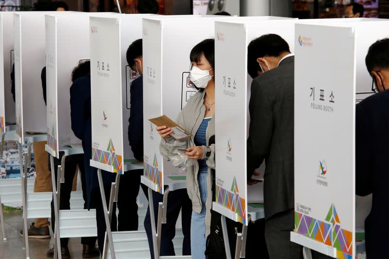 Voters cast absentee ballots for the parliamentary election at a polling station in Seoul