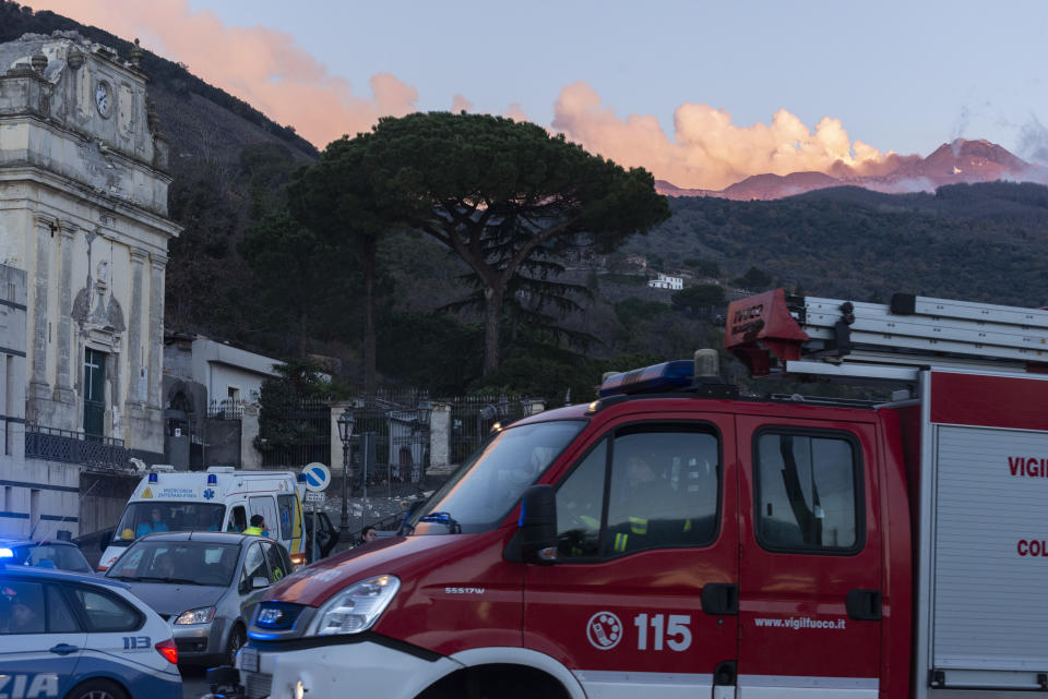 Italian Civil protection volunteers and firefighters gather near the heavily damaged church of Maria Santissima as plumes of smoke come out the Mount Enta Volcano in Fleri, Sicily Italy, Wednesday, Dec. 26, 2018. A quake triggered by Italy's Mount Etna volcano has jolted eastern Sicily, slightly injuring 10 people and prompting frightened Italian villagers to flee their homes. (AP Photo/Salvatore Allegra)