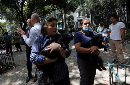 Women carrying their dogs stand outside their homes after an earthquake in Mexico City, Mexico September 19, 2017. REUTERS/Claudia Daut