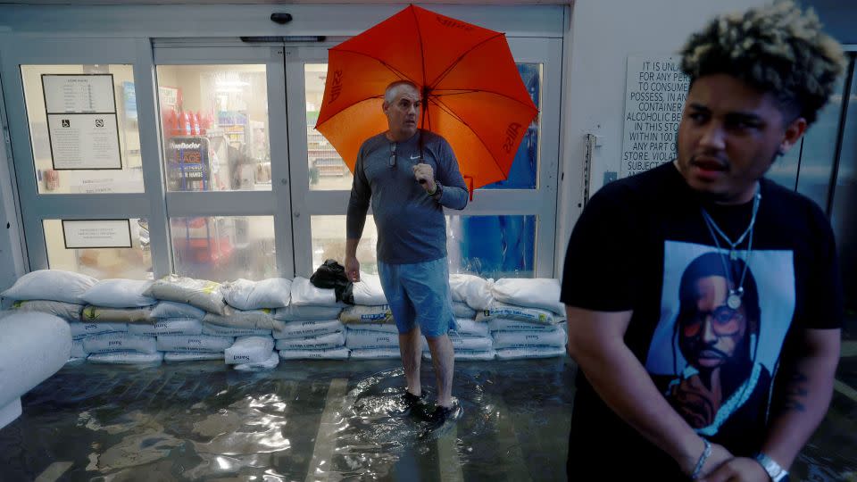Pedestrians stand at the inundated entryway of a Publix supermarket as a deluge of rain from a tropical storm in 2022 caused flooding in Miami. - Joe Raedle/Getty Images