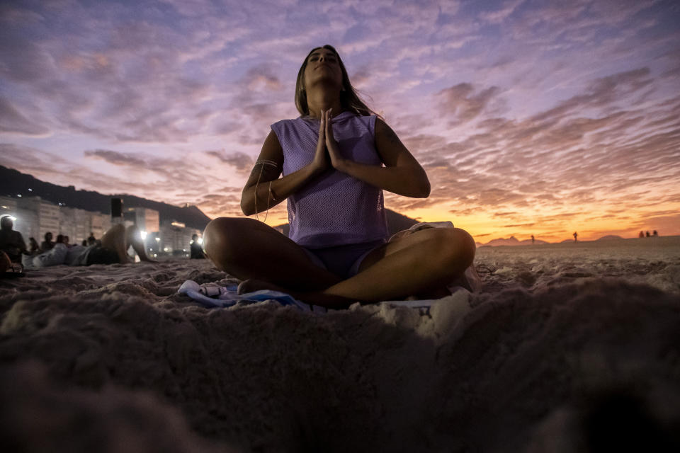 A woman sits in lotus prayer pose during the "Yoga at the Sunrise" event on Copacabana beach, in Rio de Janeiro, Saturday, June 22, 2024. The activity celebrates International Yoga Day proclaimed by the United Nations as June 21. (AP Photo/Bruna Prado)