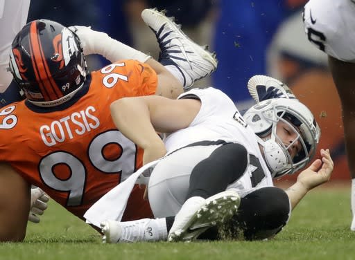 Oakland Raiders quarterback Derek Carr, right, grabs his back after being sacked by Denver Broncos defensive ends Adam Gotsis. (AP Photo)