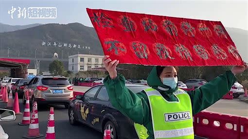 25歲女警自願前往防疫第一線，舉牌安撫駕駛的焦躁情緒。（圖／翻攝自CHINA LIVE YouTube）