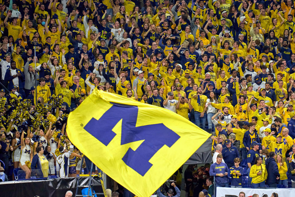 INDIANAPOLIS, IN - DECEMBER 04: Michigan Wolverines fans celebrate as a Michigan Wolverines flag is waved during the Big Ten Championship Game between the Iowa Hawkeyes and the Michigan Wolverines on December 04, 2021, at Lucas Oil Stadium, in Indianapolis, IL. (Photo by Robin Alam/Icon Sportswire via Getty Images)