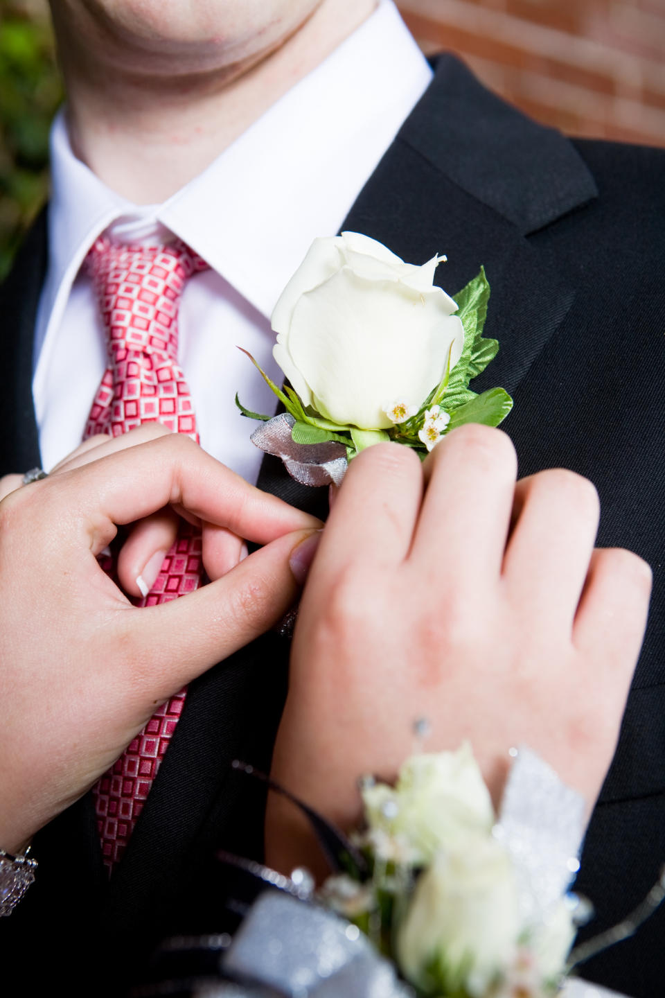 a person fastening a flower on a man's lapel
