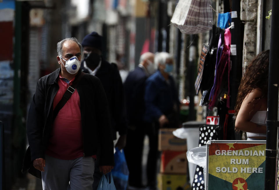 Customers stroll through Shepherd's bush market that is allowed to reopen after the COVID-19 lockdown in London, Monday, June 1, 2020. The British government has lifted some lockdown restrictions to restart social life and activate the economy while still endeavouring to limit the spread of the highly contagious COVID-19 coronavirus.(AP Photo/Frank Augstein)