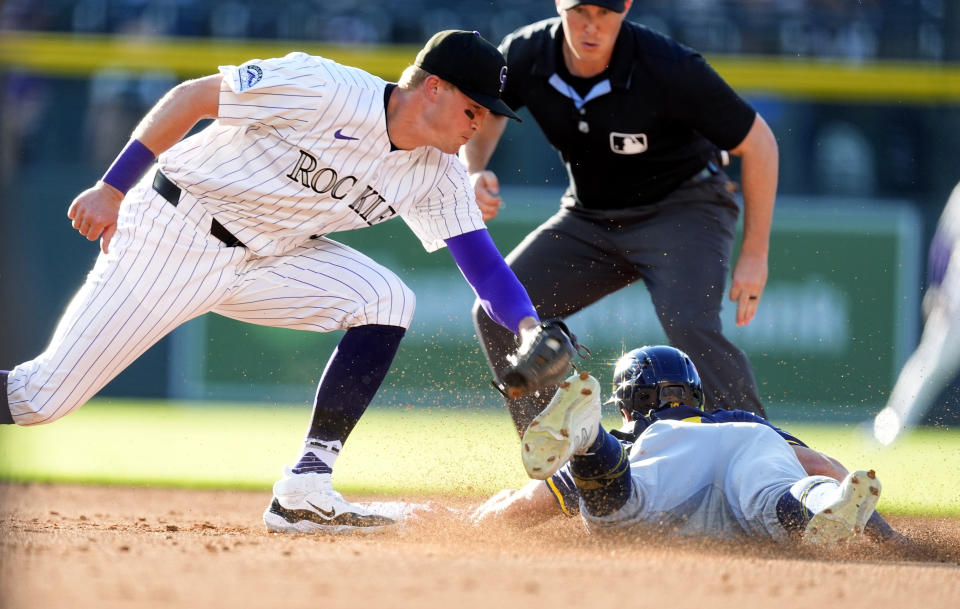 Colorado Rockies shortstop Aaron Schunk, left, applies a late tag as Milwaukee Brewers' Sal Frelick advances from first to second base on a passed ball as second base umpire Brennan Miller, back, looks on in the second inning of a baseball game Wednesday, July 3, 2024, in Denver. (AP Photo/David Zalubowski)