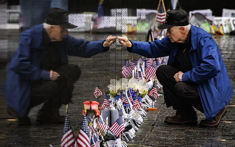 David Loesch, a 101st Airborne veteran of the Vietnam War, crouches at the Vietnam Veterans Memorial as he searches for names
