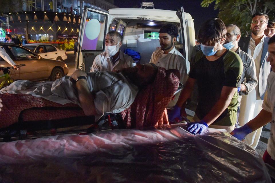 EDITORS NOTE: Graphic content / Volunteers and medical staff bring an injured man for treatment after two powerful explosions, which killed at least six people, outside the airport in Kabul on August 26, 2021. (Photo by Wakil KOHSAR / AFP) (Photo by WAKIL KOHSAR/AFP via Getty Images)