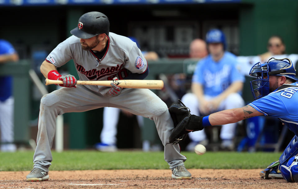 Minnesota Twins' Jake Cave, left, is hit by a pitch in front of Kansas City Royals catcher Cam Gallagher, right, during the 10th inning of a baseball game at Kauffman Stadium in Kansas City, Mo., Saturday, June 22, 2019. (AP Photo/Orlin Wagner)