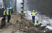 FILE - Workers and heavy machinery working on the first part of some 180 kilometers (115 miles) and 5.5 meter (18ft)-high metal wall intended to block migrants from Belarus crossing illegally into EU territory, in Tolcze, near Kuznica, Poland, Jan. 27, 2022. A year after migrants started crossing into the European Union from Belarus to Poland, Polish authorities are planning to announce Thursday that a 5.5-meter-tall steel wall along its border to the north with Belarus is set to be completed. (AP Photo/Czarek Sokolowski, File)