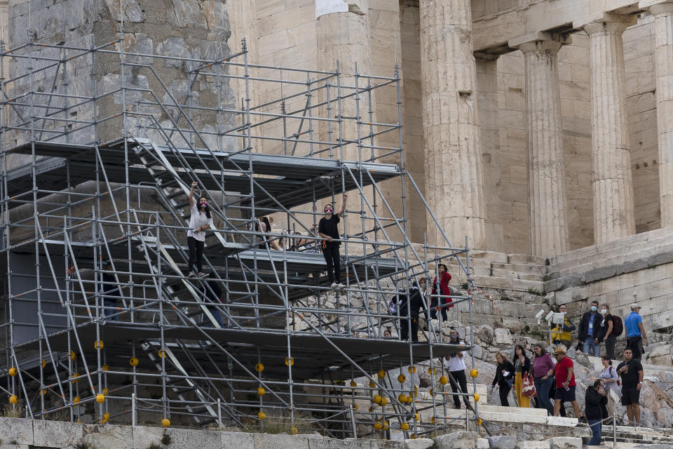 Protesters shout slogans as they climb on scaffolding at the Acropolis hill, in Athens, Greece, Sunday, Oct. 17, 2021. Three people attempted to hang a banner from the Acropolis in Athens Sunday morning in protest at the upcoming Beijing Winter Olympics but were arrested before completing their mission. (AP Photo/Yorgos Karahalis)