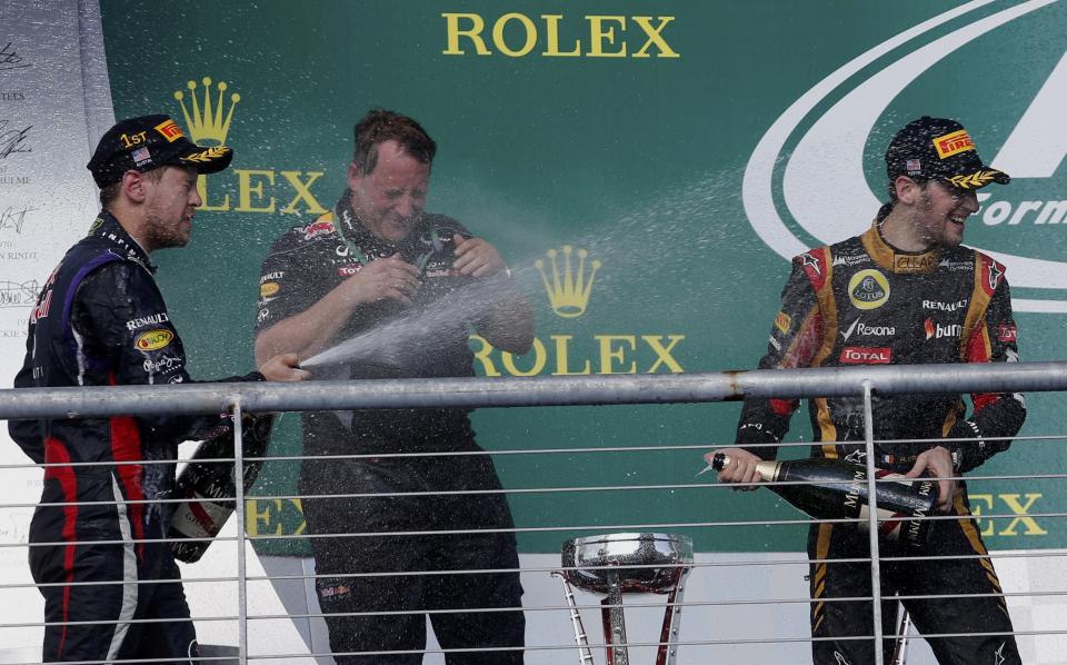 Red Bull Formula One driver Sebastian Vettel (L) of Germany and Lotus Formula One driver Romain Grosjean of France (R) spray champagne next to Red Bull Racing's Head of IT Matt Cadieux during celebrations on the podium after the Austin F1 Grand Prix at the Circuit of the Americas in Austin November 17, 2013. Vettel won the race with teammate Mark Webber (unseen) coming in second and Grosjean third.