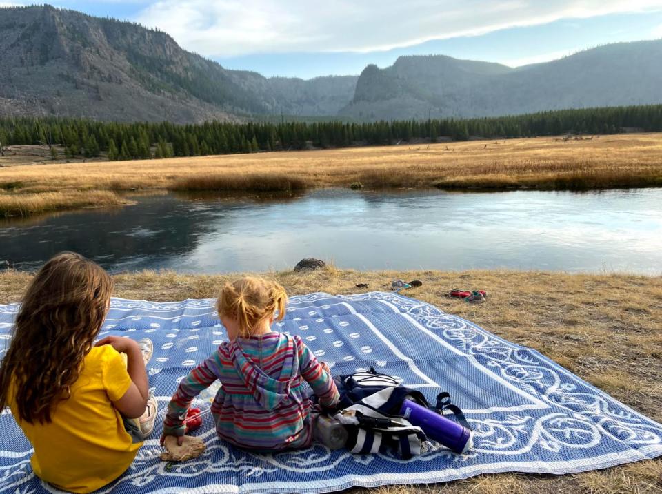 The author's daughters enjoying a picnic along the Firehole River in Yellowstone National Park in October 2020. (Photo: Courtesy of Kelly Burch)