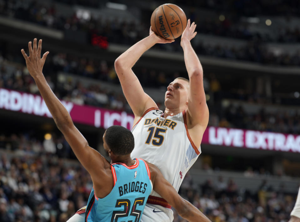 Denver Nuggets center Nikola Jokic, back, shoots over Phoenix Suns forward Mikal Bridges in the first half of an NBA basketball game, Sunday, Dec. 25, 2022, in Denver. (AP Photo/David Zalubowski)