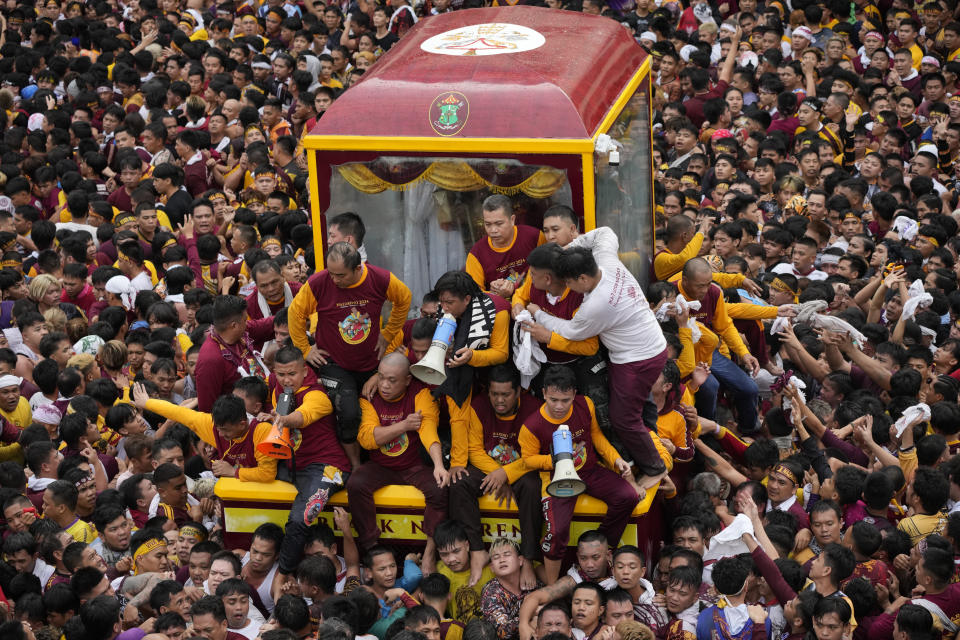 Devotees react as they try to block others from climbing on the glass-covered cart carrying Black Nazarene during its annual procession which was resumed after a three-year suspension due to the coronavirus pandemic on Tuesday, Jan. 9, 2024 in Manila, Philippines. A mammoth crowd of mostly barefoot Catholic devotees joined a chaotic procession through downtown Manila Tuesday to venerate a centuries-old black statue of Jesus Christ with many praying for peace in the Middle East where Filipino relatives work. (AP Photo/Aaron Favila)