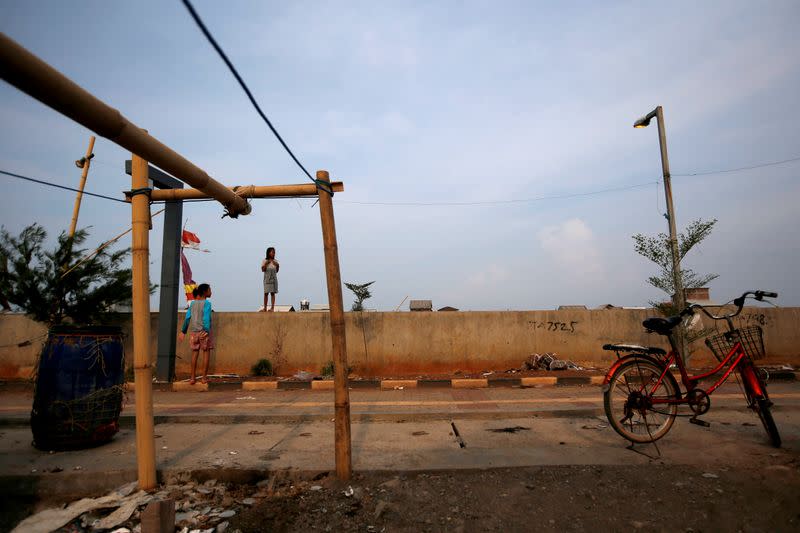 A girl stands on a wall near a port at Tambaklorok village, which has been affected by rising sea level and land subsidence, in Semarang