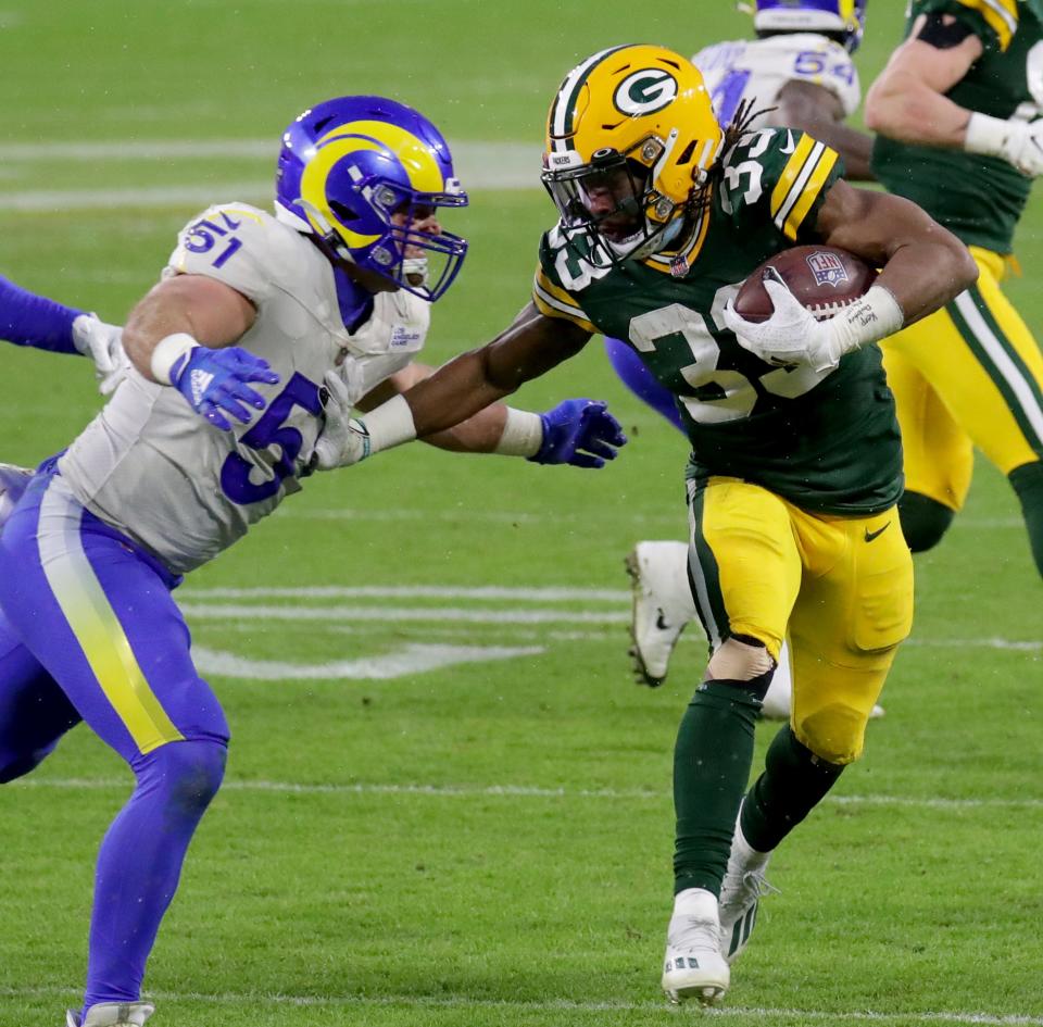 Green Bay Packers running back Aaron Jones (33) rushes past Los Angeles Rams inside linebacker Troy Reeder (51) during the 2nd quarter of the Green Bay Packers Los Angeles Rams NFC divisional playoff game Saturday, Jan. 16, 2021 at Lambeau Field in Green bay, Wis.