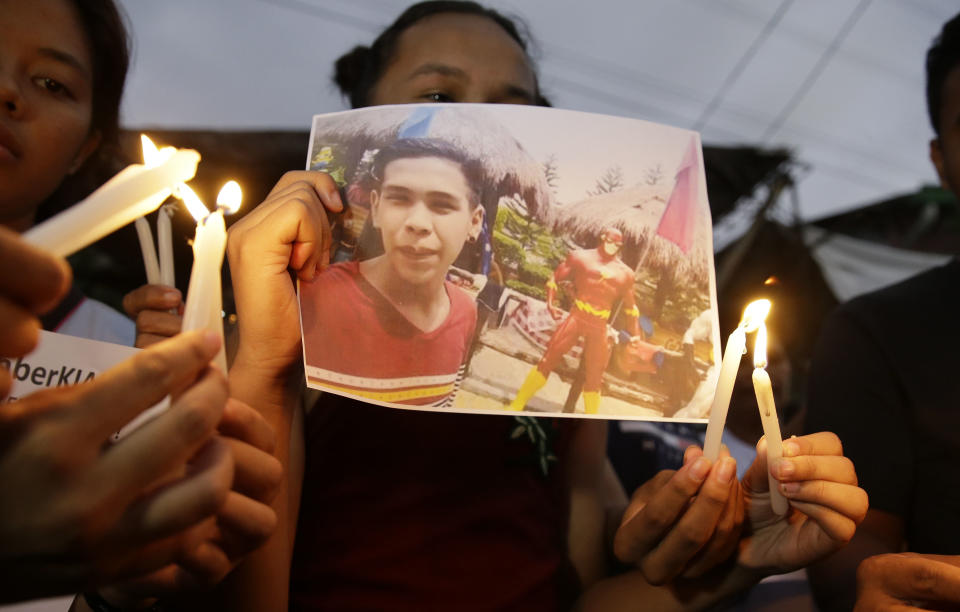 Activists light candles in front of the picture of 17-year-old student Kian Loyd delos Santos in Caloocan, metropolitan Manila, Philippines on Thursday, Nov. 29, 2018. A Philippine court has found three police officers guilty of murdering delos Santos they alleged was a drug dealer in the first known conviction of a wrongful death under the president's deadly anti-drugs crackdown. (AP Photo/Aaron Favila)