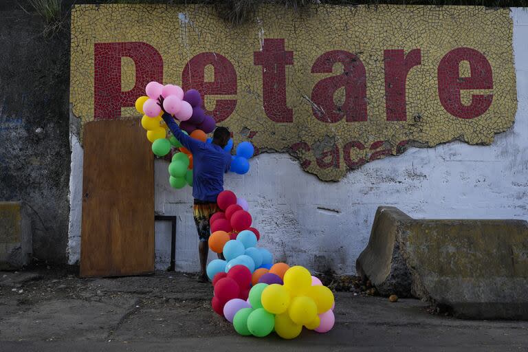 Un residente quita globos que decoraban una pared en el barrio de Petare 