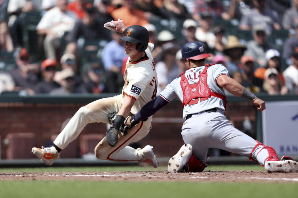San Francisco Giants' Tyler Fitzgerald, left, is tagged out at home by Washington Nationals catcher Drew Milas, right, on a runner's fielder's choice hit by Lamont Wader Jr. during the sixth inning of a baseball game in San Francisco, Wednesday, April 10, 2024. (AP Photo/Jed Jacobsohn)