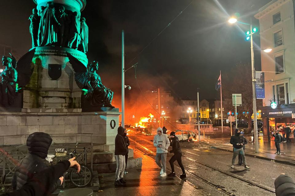 TOPSHOT - Flames rise from a car and a bus, set alight at the junction of Bachelors Walk and the O'Connell Bridge, in Dublin on November 23, 2023, as people took to the streets in protest following the stabbings earlier in the day. Protesters in Dublin on Thursday torched a car and fought police, an AFP journalist reported, after three children were injured in a suspected school stabbing that social media rumours attributed to a foreign national. (Photo by Peter MURPHY / AFP) (Photo by PETER MURPHY/AFP via Getty Images)