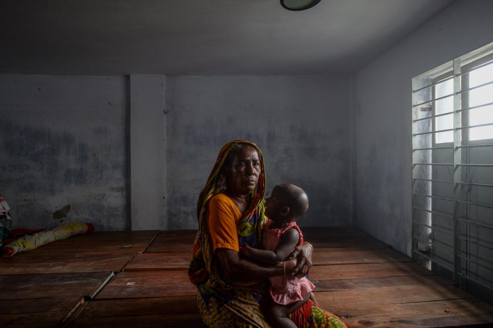 A resident carrying a child rests in a shelter ahead of the expected landfall of cyclone Amphan in Dacope of Khulna district on May 20, 2020. - Several million people were taking shelter and praying for the best on Wednesday as the Bay of Bengal's fiercest cyclone in decades roared towards Bangladesh and eastern India, with forecasts of a potentially devastating and deadly storm surge. Authorities have scrambled to evacuate low lying areas in the path of Amphan, which is only the second "super cyclone" to form in the northeastern Indian Ocean since records began. (Photo by Munir Uz zaman / AFP) (Photo by MUNIR UZ ZAMAN/AFP via Getty Images)