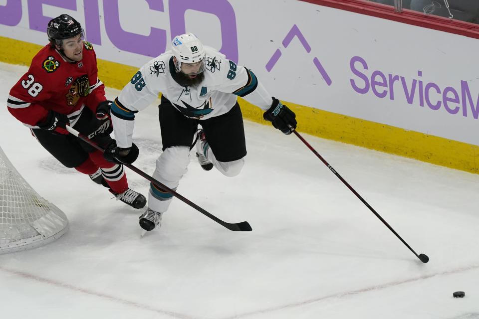 San Jose Sharks defenseman Brent Burns, right, chases the puck past Chicago Blackhawks left wing Brandon Hagel during the second period of an NHL hockey game in Chicago, Sunday, Nov. 28, 2021. (AP Photo/Nam Y. Huh)