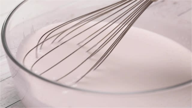 Mixing kueh lapis batter with a metal whisk