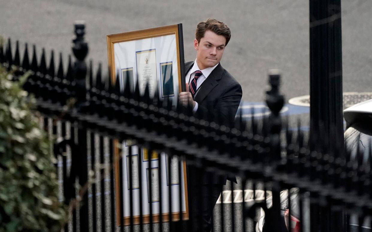 A man carries framed items to a car as he leave the Eisenhower Executive Office building, inside the White House complex - Gerald Herbert /AP