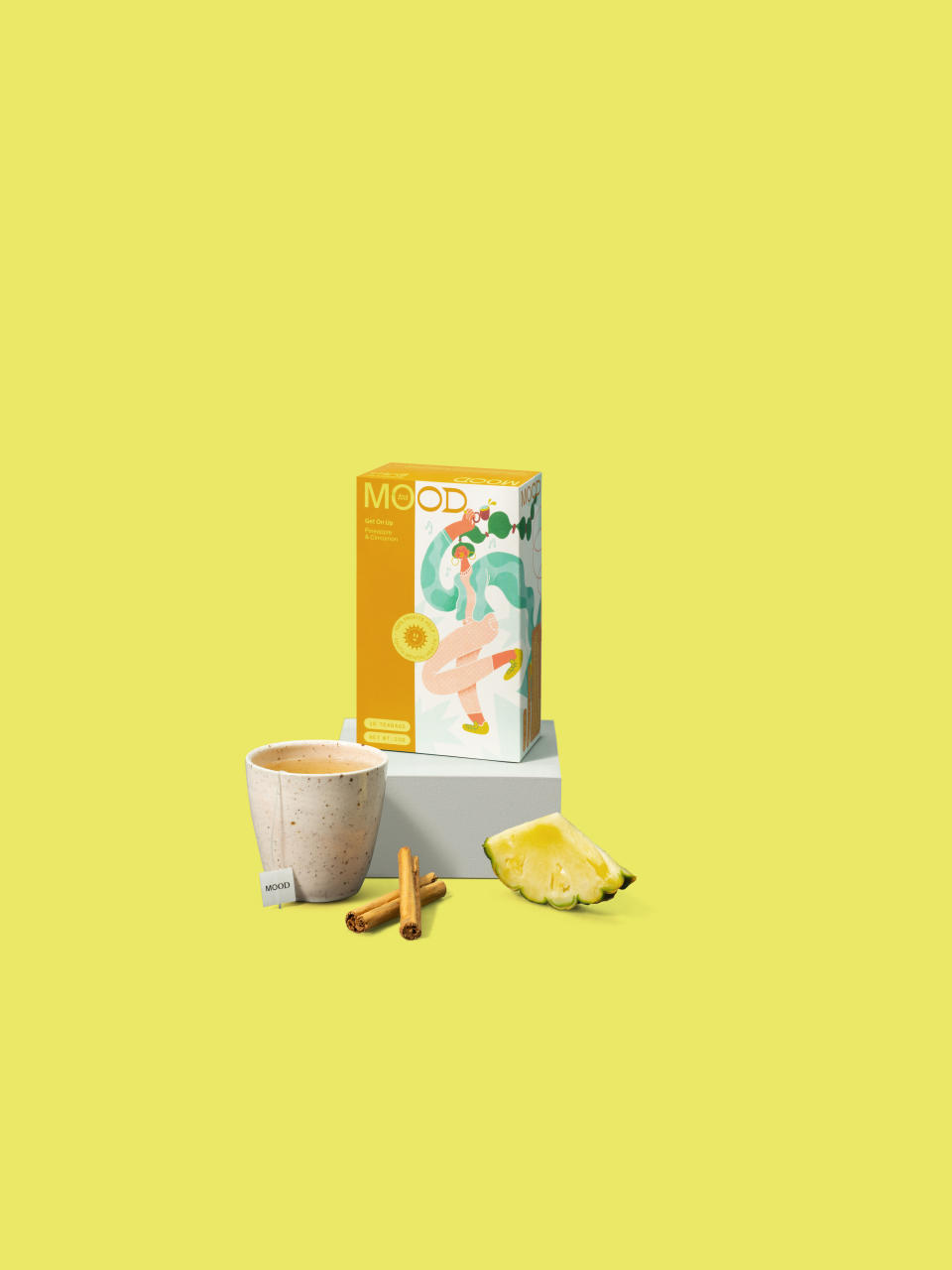 Get On Up MOOD tea on a soft yellow background with a cuppa, cinnamon and pineapple