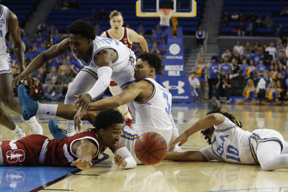 Stanford guard Bryce Wills, bottom, vies for a loose ball with UCLA guard David Singleton, top, guard Jules Bernard (3) and guard Tyger Campbell (10) during the first half of an NCAA college basketball game in Los Angeles, Wednesday, Jan. 15, 2020. (AP Photo/Chris Carlson)