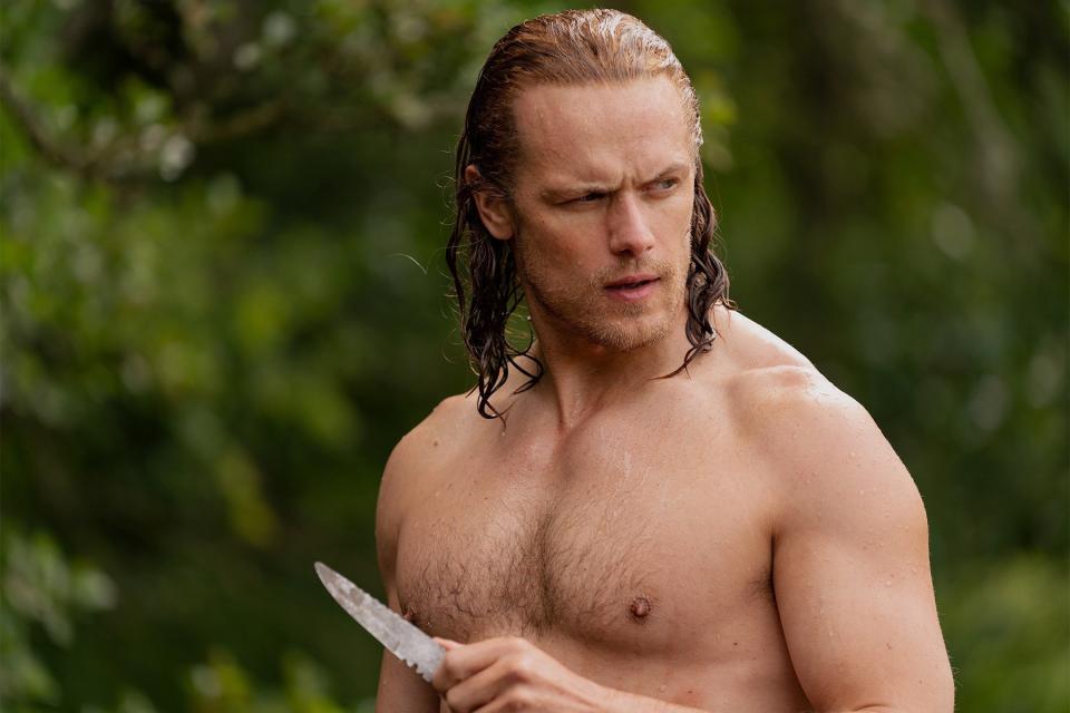 Jamie wielding a knife while shirtless in the wilderness