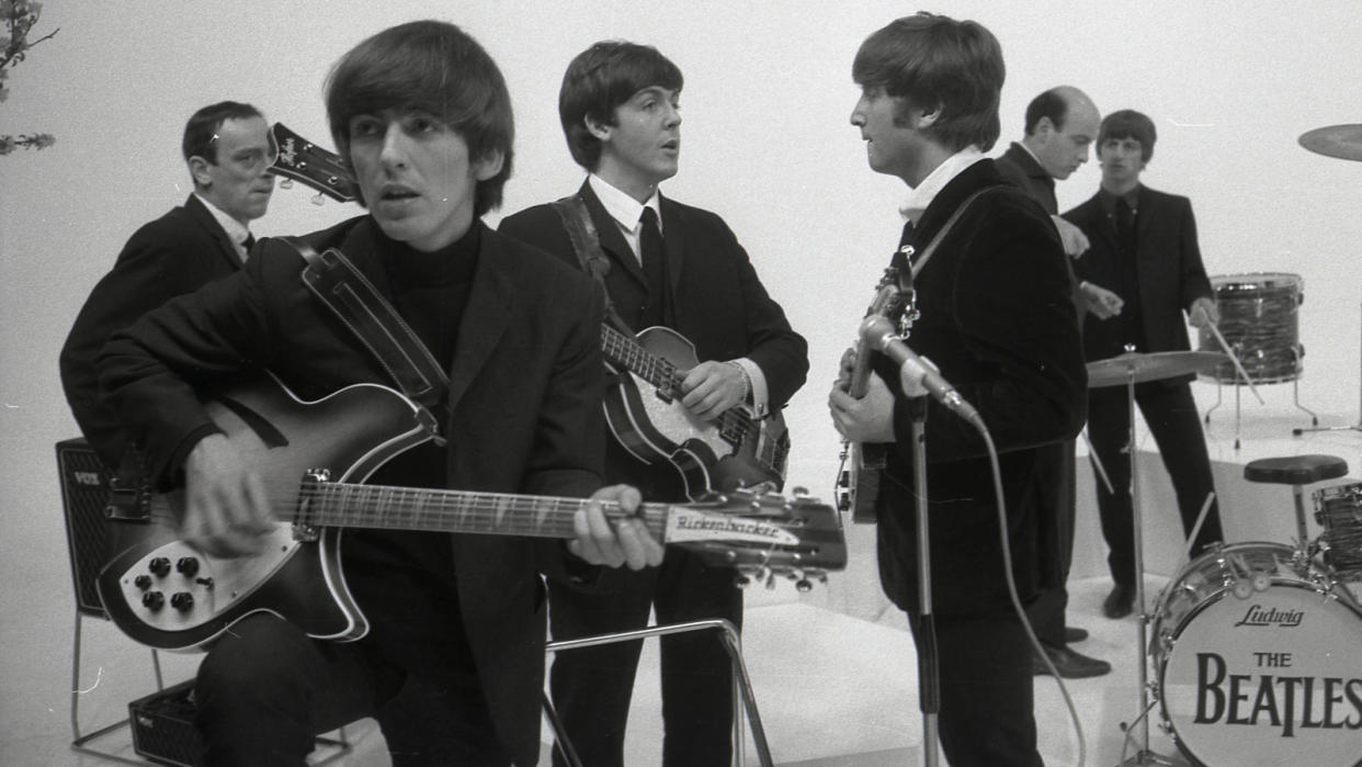  Harrison with his Rickenbacker 360/12 on the set of the Beatles’ 1964  film, A Hard Day’s Night. (From left) Actor John Junkin, Harrison, Paul  McCartney, John Lennon, director Richard Lester and Ringo Starr 