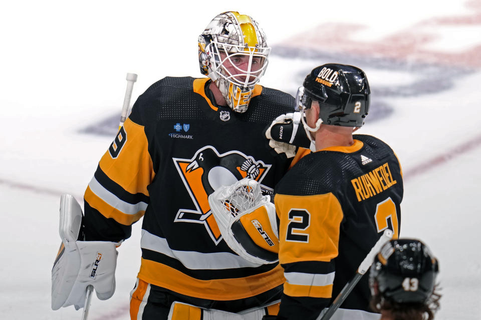 Pittsburgh Penguins goaltender Alex Nedeljkovic, left, celebrates with Chad Ruhwedel (2) after the team's win over the Calgary Flames in an NHL hockey game in Pittsburgh, Saturday, Oct. 14, 2023. (AP Photo/Gene J. Puskar)