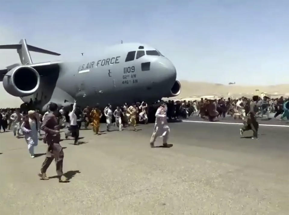 Hundreds of people run alongside a U.S. Air Force C-17 transport plane as it moves down a runway of the international airport, in Kabul, Afghanistan, Monday, Aug.16. 2021. Thousands of Afghans have rushed onto the tarmac at the airport, some so desperate to escape the Taliban capture of their country that they held onto the American military jet as it took off and plunged to death. (Verified UGC via AP)