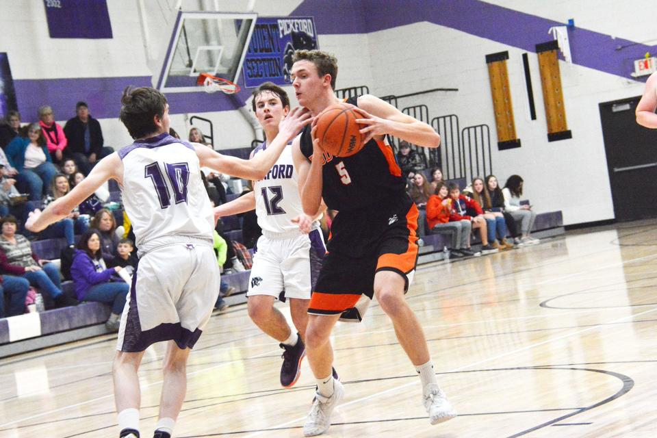 Tate Besteman (5) of Rudyard drives in the lane, while Pickford's Quincy Michalski (10) and Zach Harrison (12) defend during an Eastern UP Conference basketball game Thursday night.