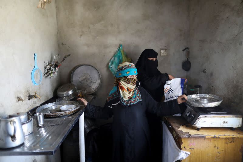 Umm-Hani al-Sharaabi shows empty plates as she stands with her daughter-in-law Umm-Zakaria al-Sharaabi in their kitchen in Sanaa