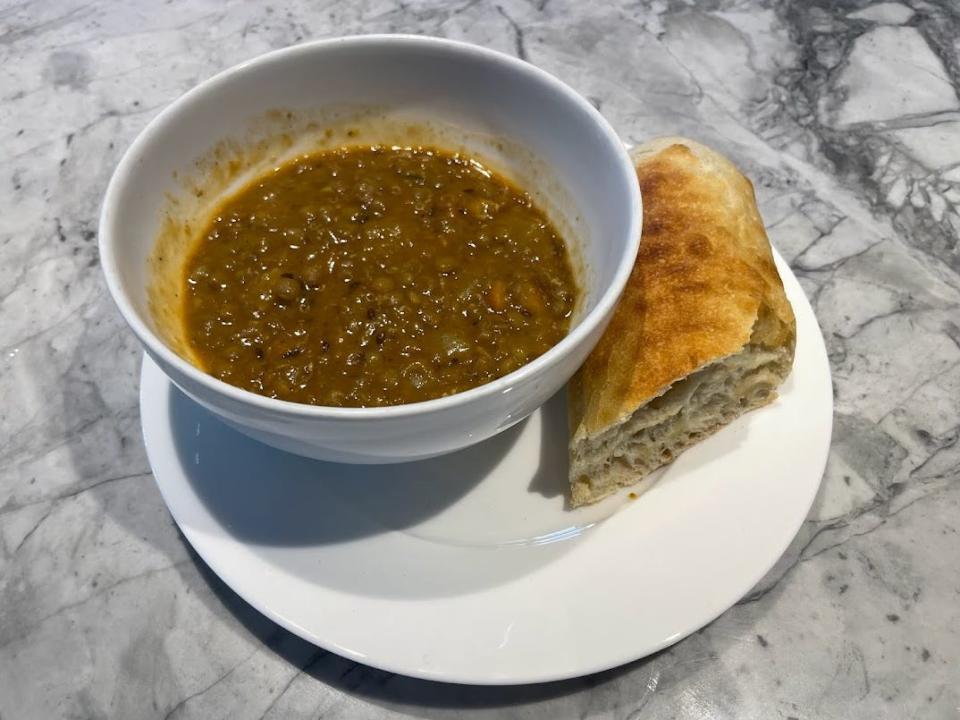 trader joes lentil soup in a bowl with a piece of bread next to it