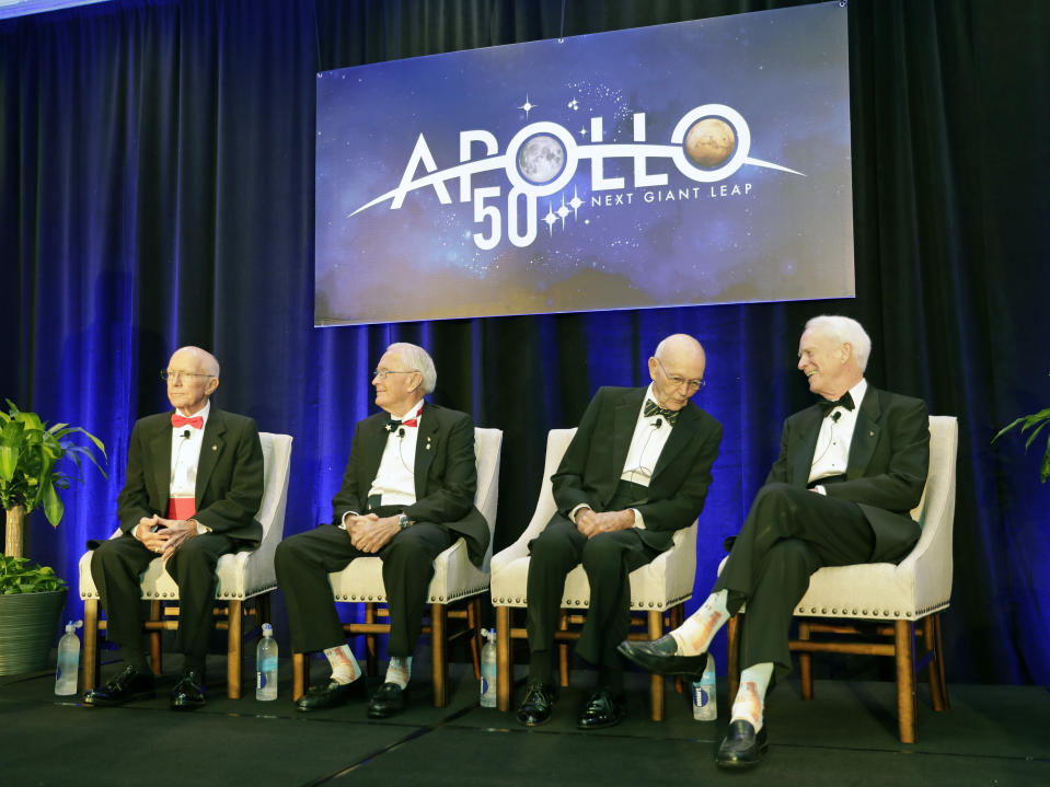 Apollo Legends attend a news conference from left, Gerry Griffin, Apollo flight director, and Charlie Duke, Apollo 16 astronaut, take their seats as Mike Collins, Apollo 11 astronaut admires Apollo 9 astronaut Rusty Schweickart's socks featuring a Saturn V rocket, during a news conference Tuesday, July 16, 2019, in Cocoa Beach, Fla. (AP Photo/John Raoux)