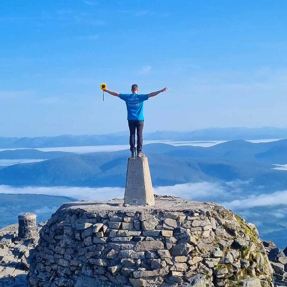 Ryan holding a sunflower at the top of Ben Nevis, Scotland. (PA Real Life/Collect)